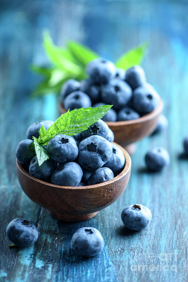 Bowl of fresh blueberries on blue rustic wooden table closeup. Photograph by Jelena Jovanovic