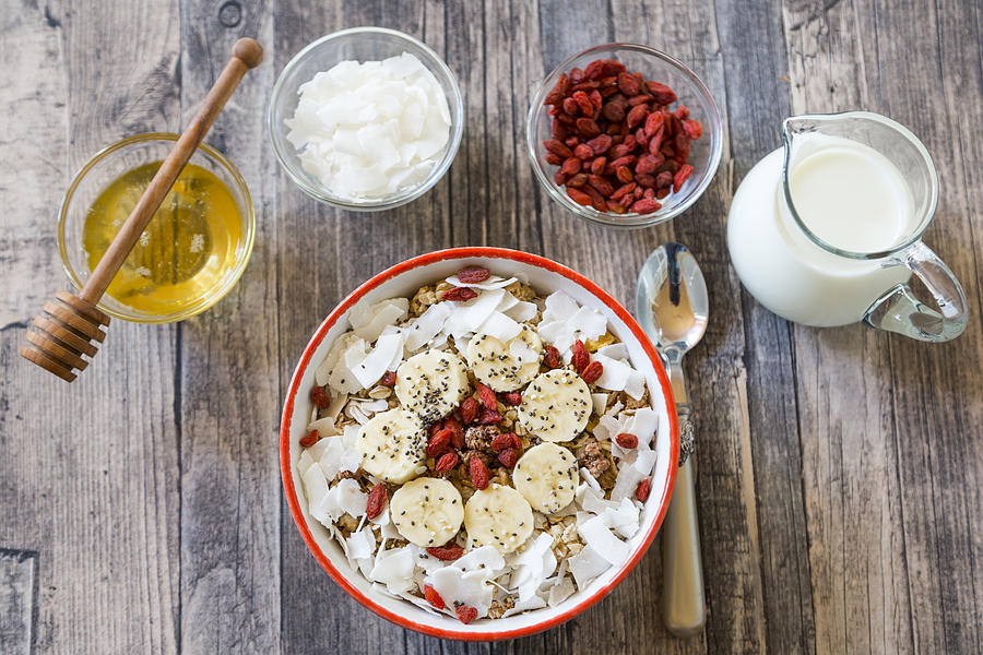 Bowl of muesli with banana slices, chia seeds, coconut chips and goji berries Photograph by Westend61
