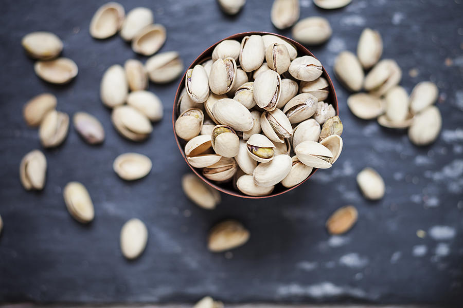 Bowl of roasted and salted pistachios on slate Photograph by Westend61