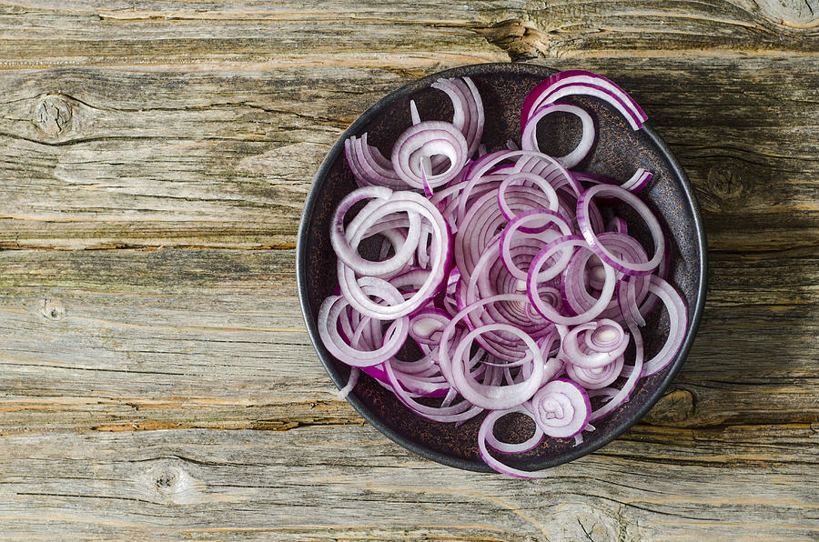 Bowl of sliced red onions on wood Photograph by Westend61