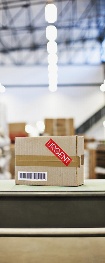 Box marked urgent in shipping area Photograph by Paul Bradbury