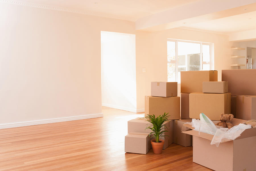 Boxes stacked on wooden floor of new house Photograph by Martin Barraud