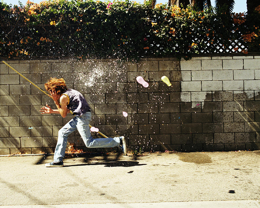 Boy (13-15) in water fight, running from water balloons Photograph by Sean Murphy
