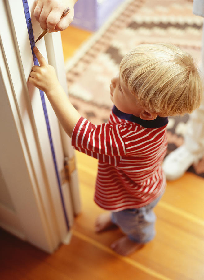 Boy (3-4) reading height measurement on door frame Photograph by Ryan McVay