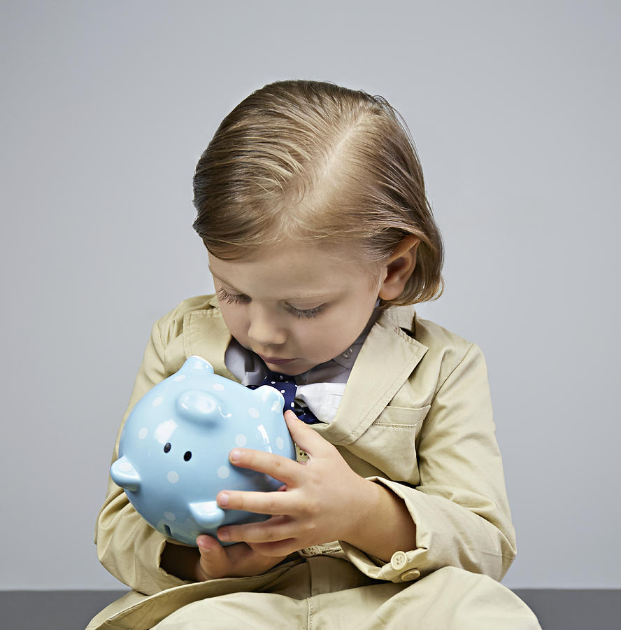 Boy (3-5) looking into piggy bank Photograph by Compassionate Eye Foundation