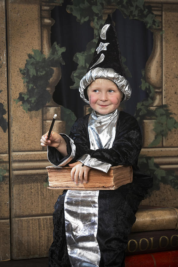 Boy (3-5) on stage in wizard costume, looking away, smiling Photograph by Richard Lewisohn