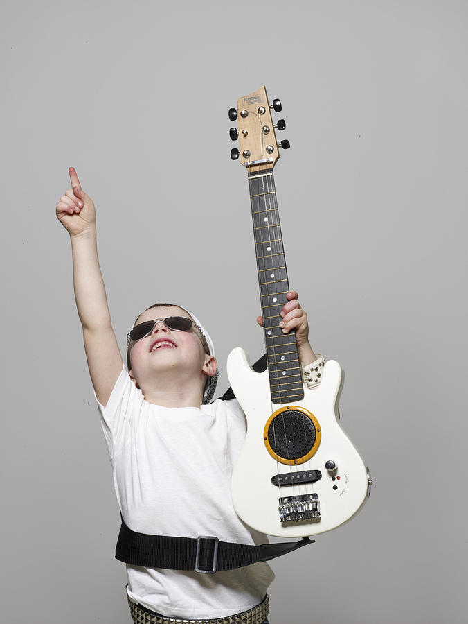 Boy (4-6) dressed as rock musician pointing upwards Photograph by Michael Greenberg