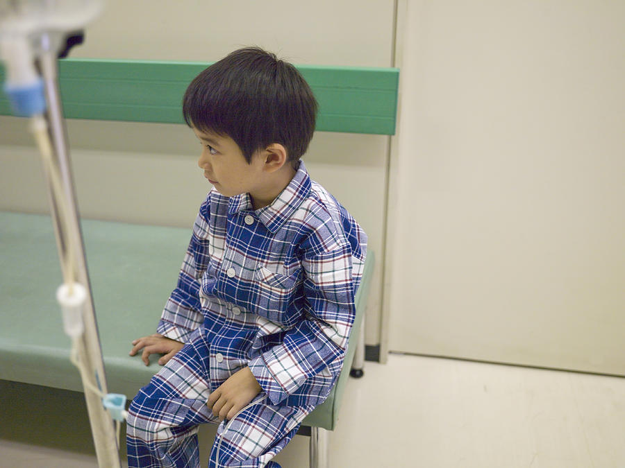 Boy (5-6) sitting with medicine drip in hospital corridor Photograph by Michael H
