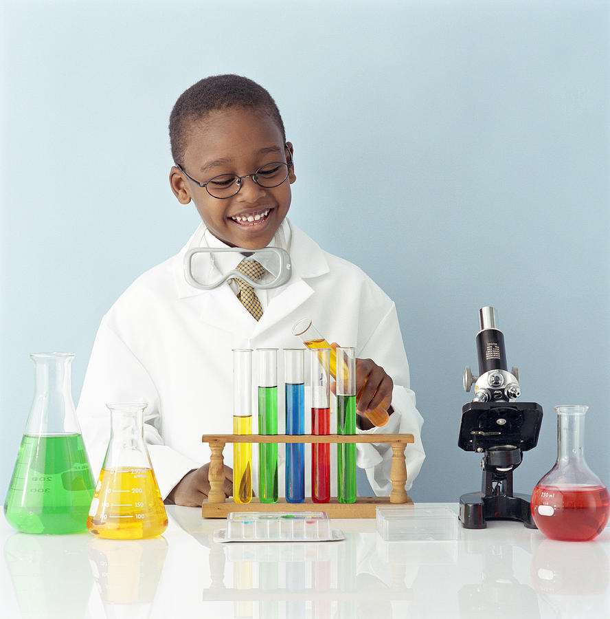 Boy (5-7) wearing white coat holding test tube in laboratory, smiling Photograph by Digital Vision