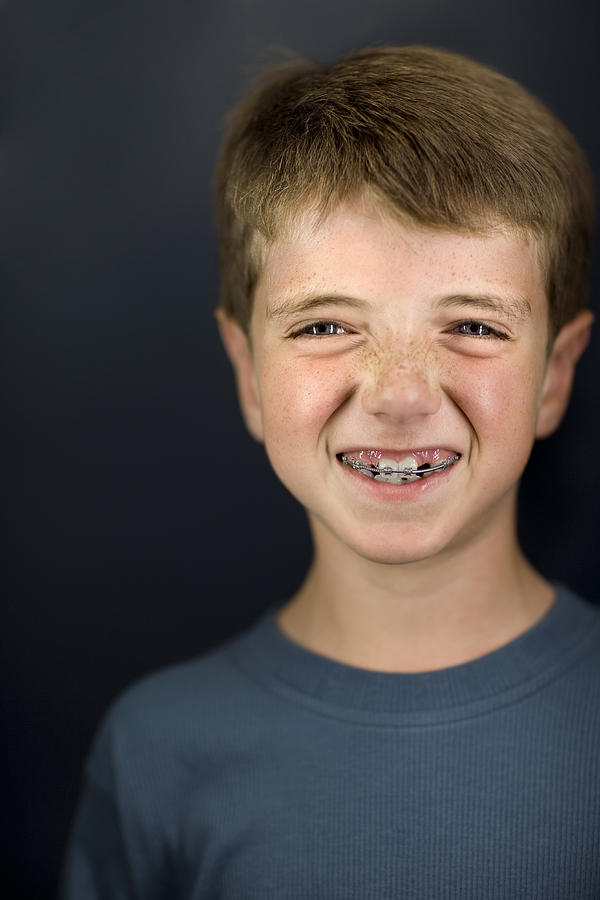 Boy (6-7) with brace, smiling, close-up, portrait Photograph by David Sacks