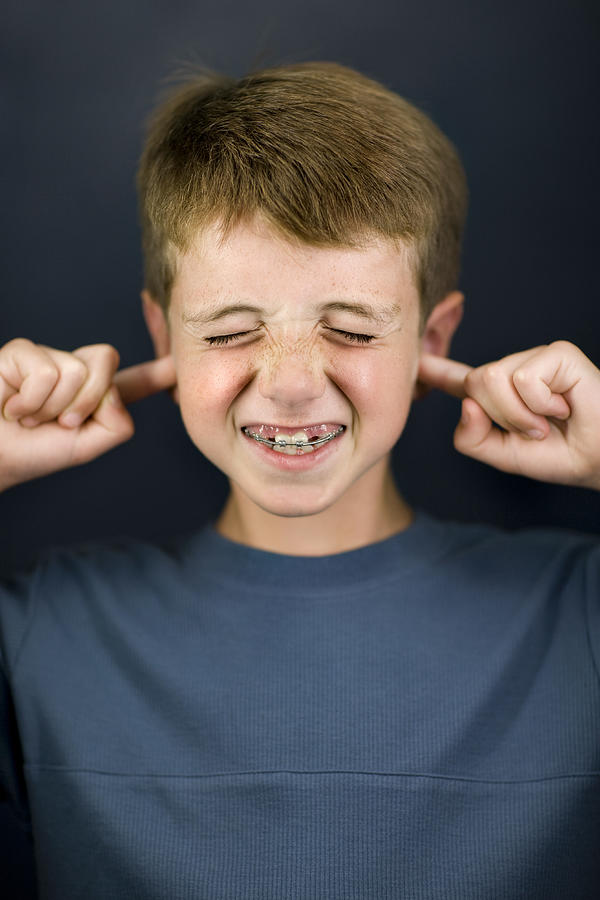 Boy (6-7) with fingers in ears, close-up Photograph by David Sacks