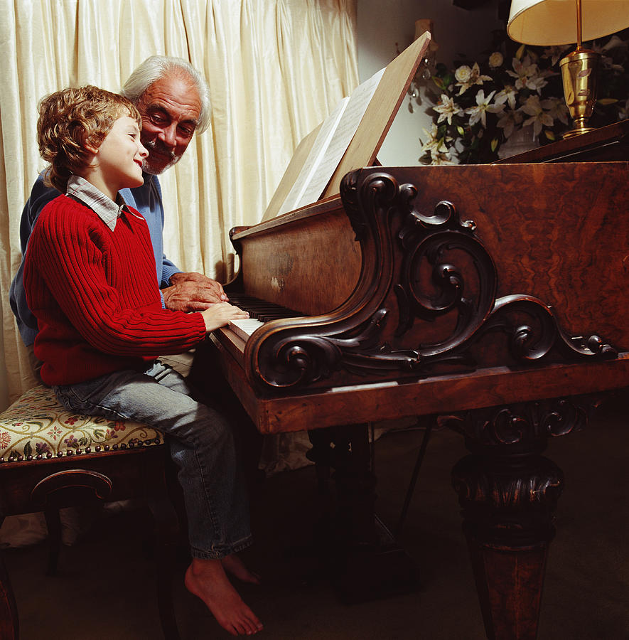 Boy (6-8) and grandfather playing the piano, smiling, side view Photograph by Chev Wilkinson