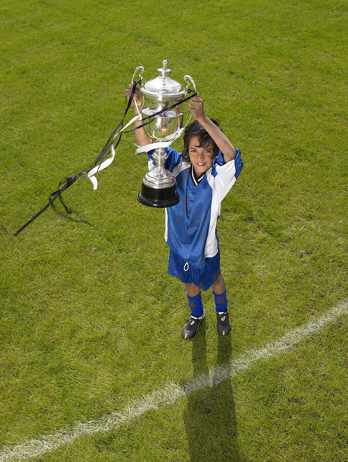 Boy (8-10) footballer holding trophy, portrait, elevated view Photograph by Michael Blann