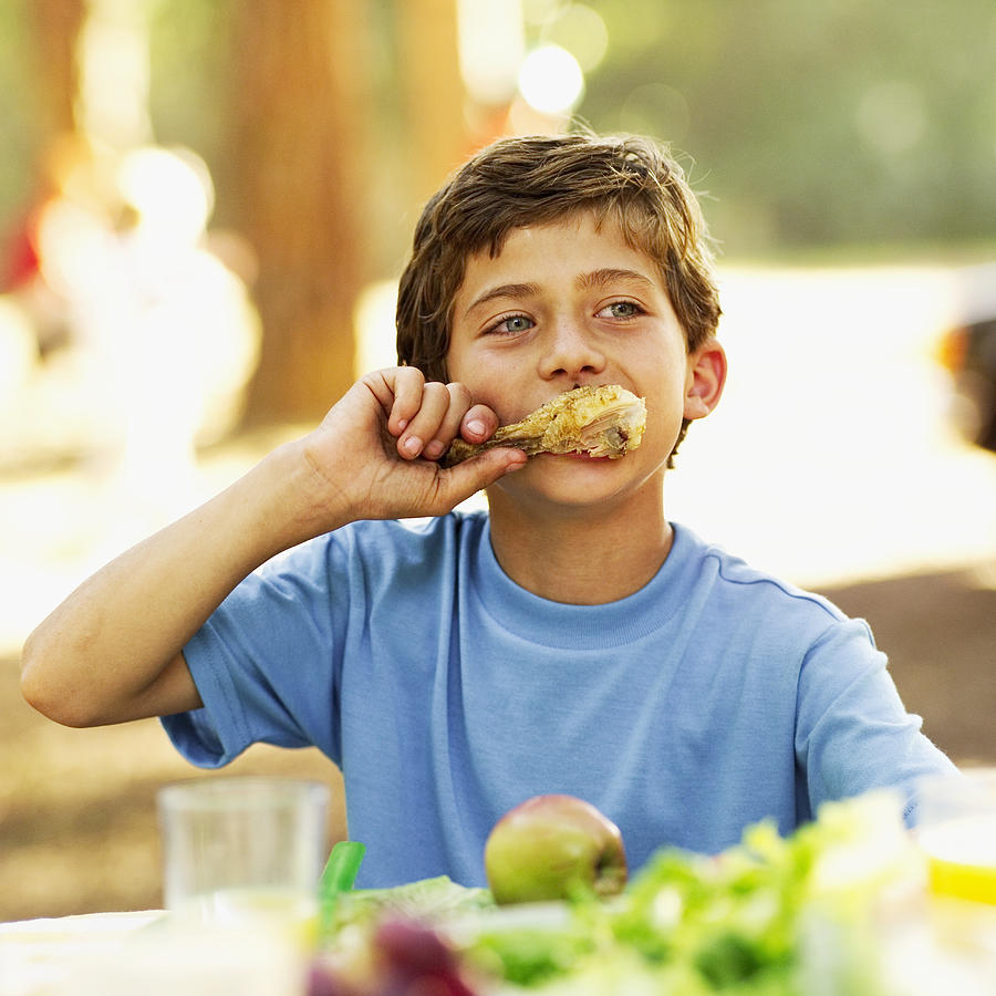 Boy (9-10) At A Picnic Eating A Chicken Drumstick Photograph by Stockbyte