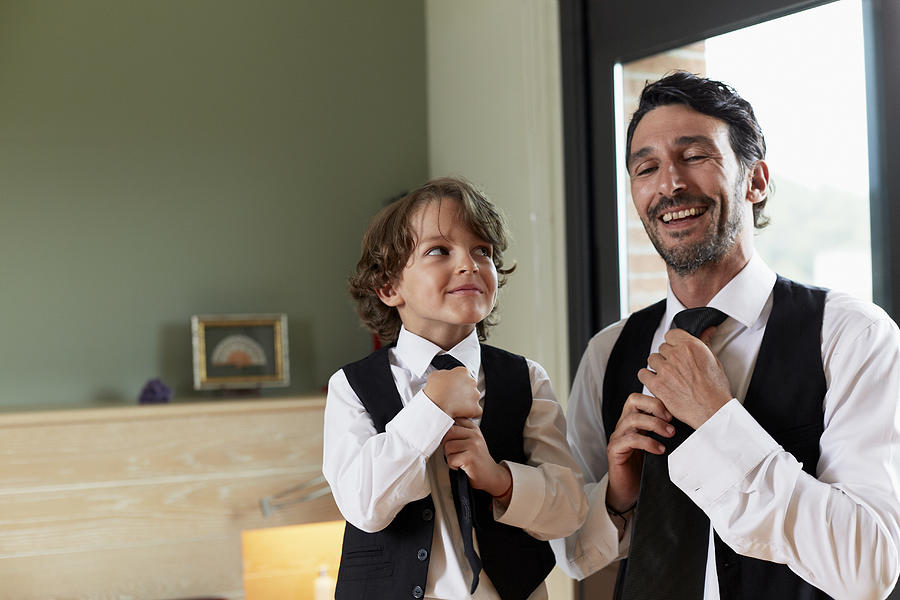 Boy adjusting tie while looking at father Photograph by Morsa Images