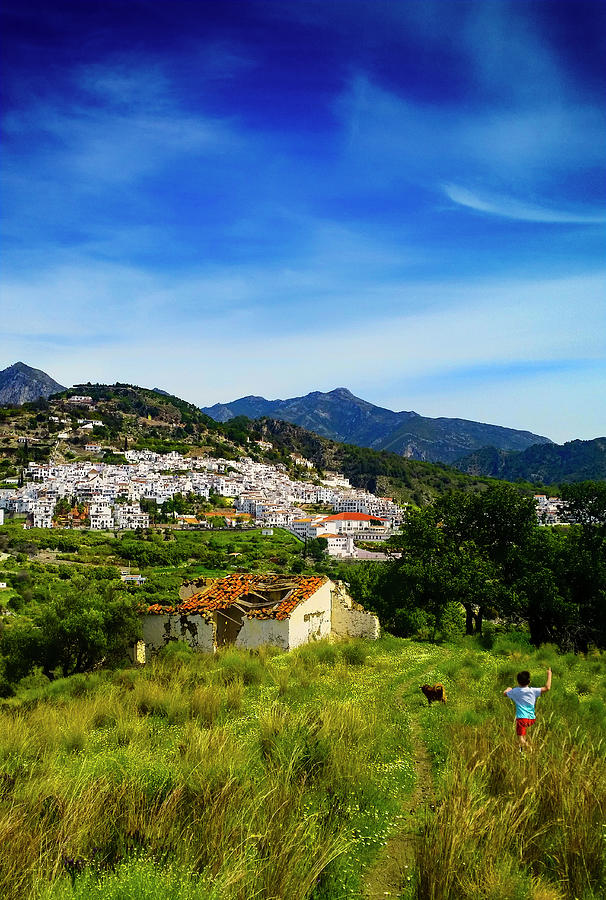 Boy and dog run to a deserted farmhouse over looking Frigiliana, Costa del Sol, Malaga Province Photograph by Panoramic Images