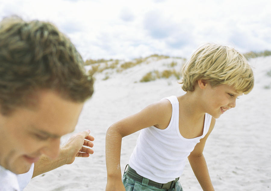 Boy and father running on beach Photograph by Sigrid Olsson