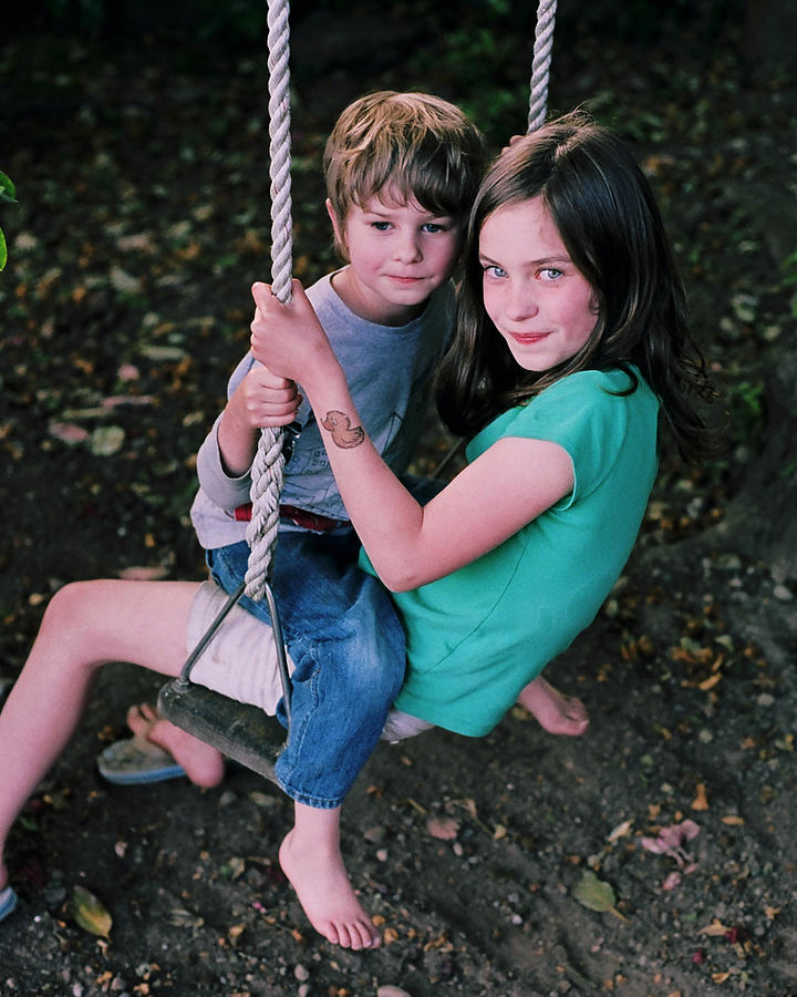 Boy and girl playing on swing Photograph by Matt Carey