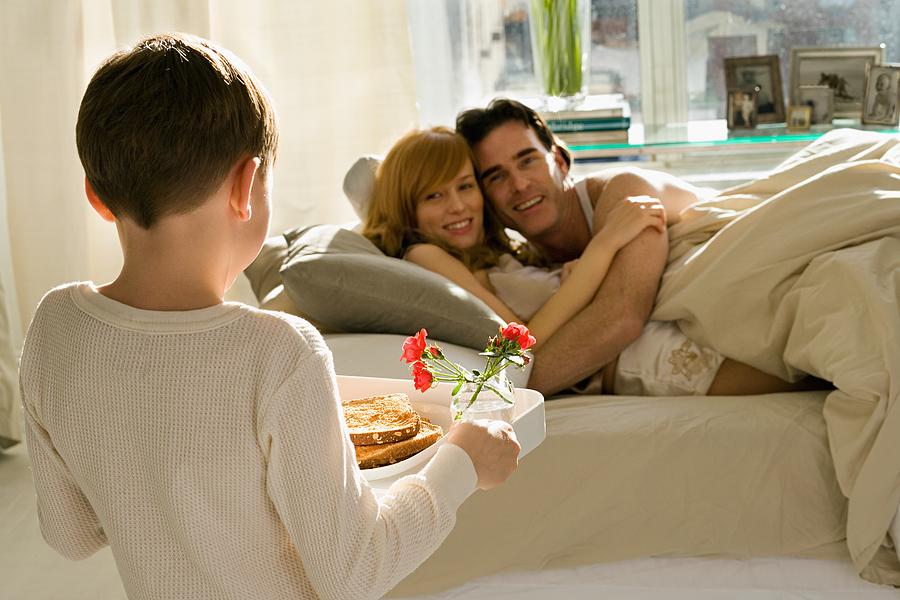 Boy bringing breakfast to parents in bed Photograph by Image Source
