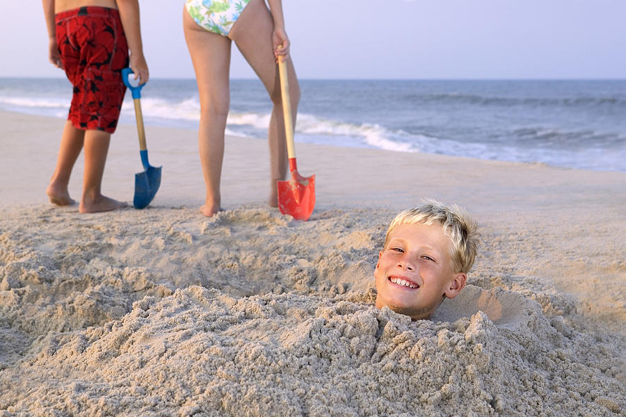 Boy buried in sand Photograph by Thinkstock Images