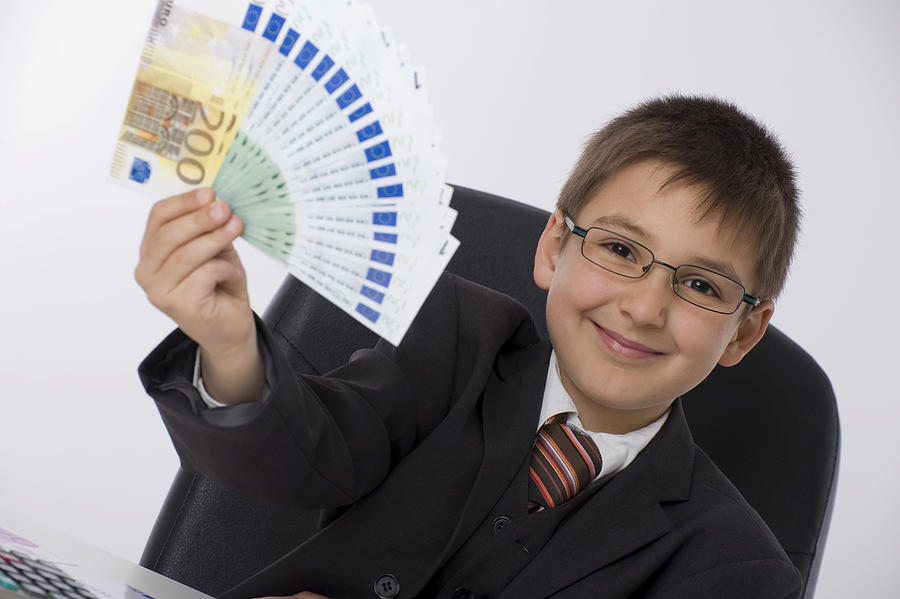 Boy dressed as a businessman holding a fan of banknotes Photograph by Michaela Begsteiger