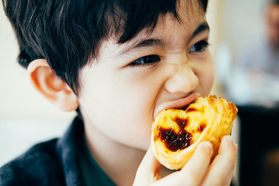 Boy eating pastel de nata Photograph by © Peter Lourenco