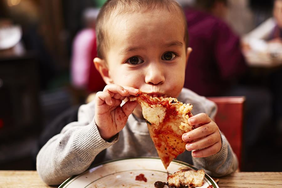 Boy eating pizza in restaurant Photograph by Jpm