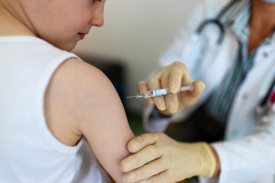 Boy getting a flu or coronavirus vaccine in the clinic Photograph by Luis Alvarez