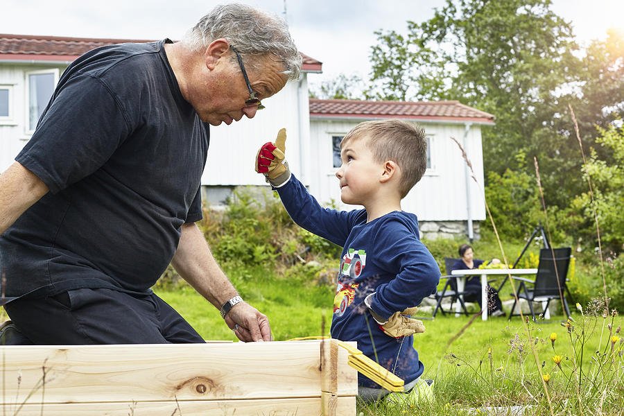 Boy helping Grandfather with joinery Photograph by Bjarte Rettedal