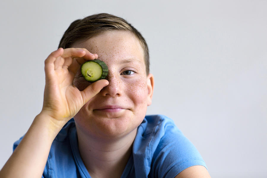 Boy holding cucumber over eye Photograph by Gombert, Sigrid/science Photo Library
