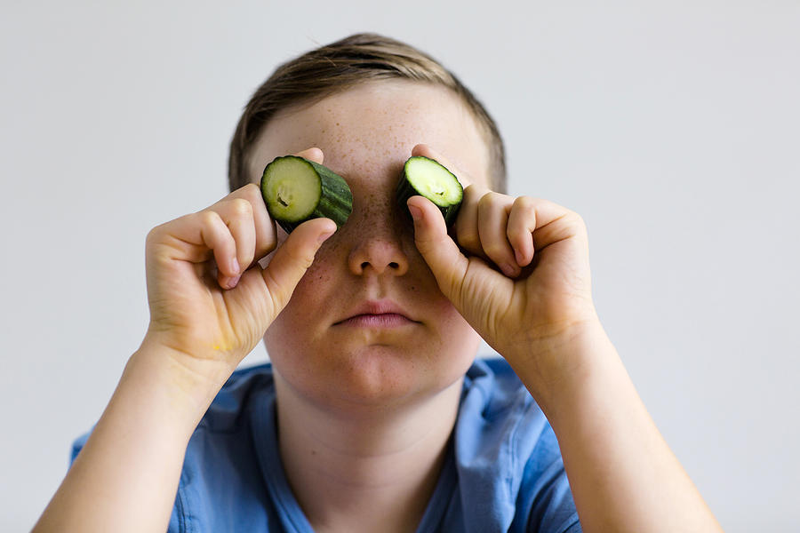 Boy holding cucumber over eyes Photograph by Gombert, Sigrid/science Photo Library