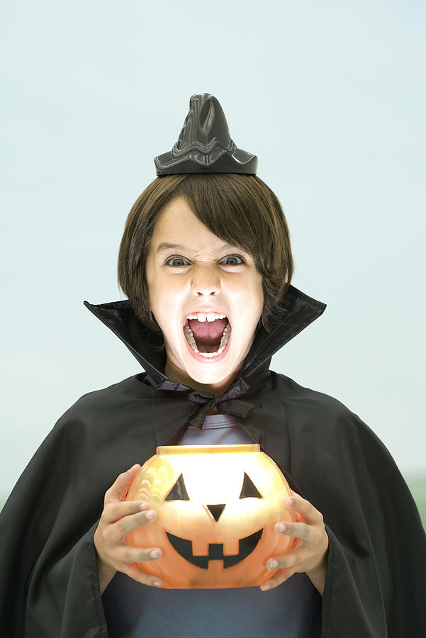 Boy holding jack o lantern, looking at camera, open mouth, portrait Photograph by PhotoAlto/Odilon Dimier