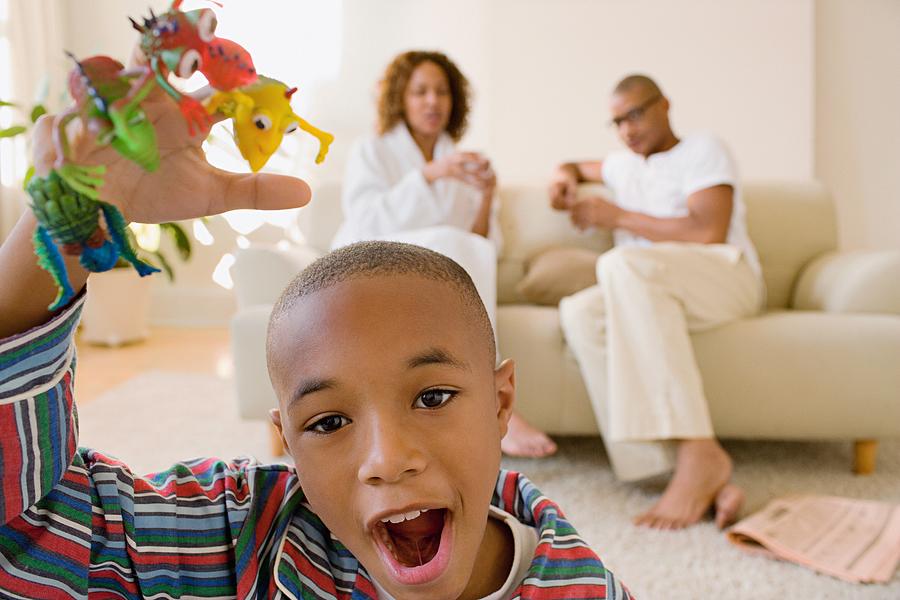 Boy in living room playing with monster finger puppets Photograph by Image Source