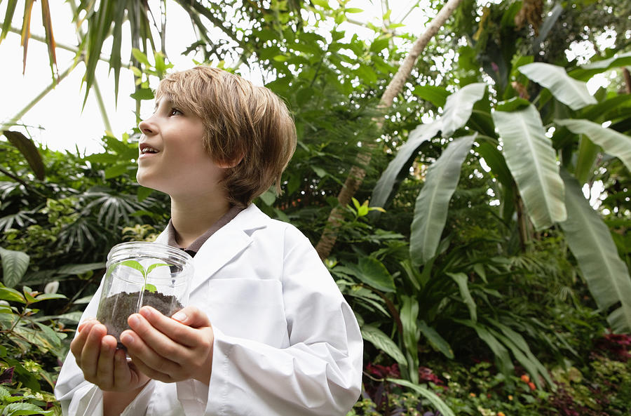 Boy In White Lab Coat Holding A Small Plant Photograph by Compassionate Eye Foundation/Noel Hendrickson