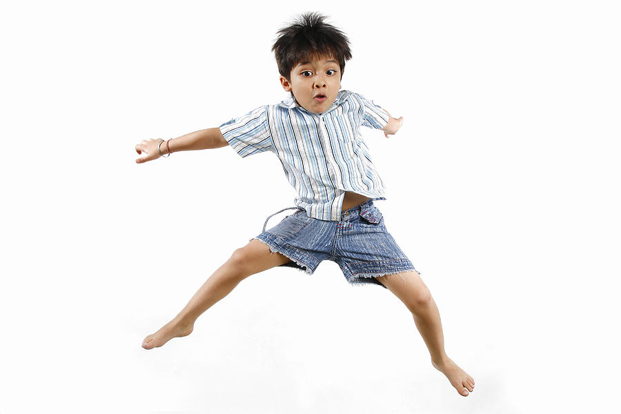 Boy jumping with his legs apart Photograph by WIN-Initiative/Neleman