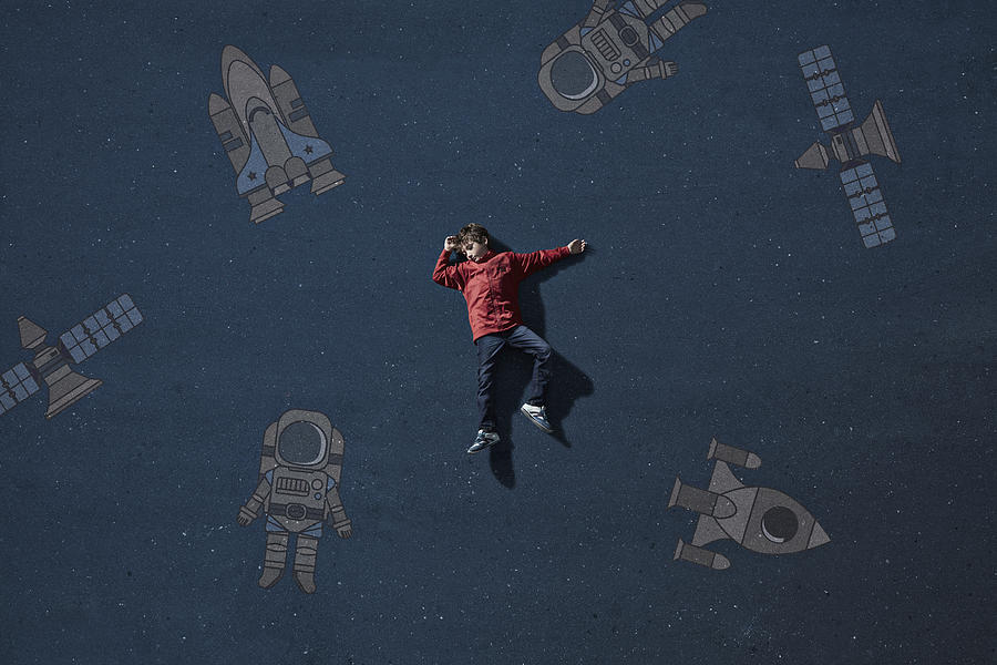 Boy laying on painted imaginary background among space travel objects Photograph by Klaus Vedfelt