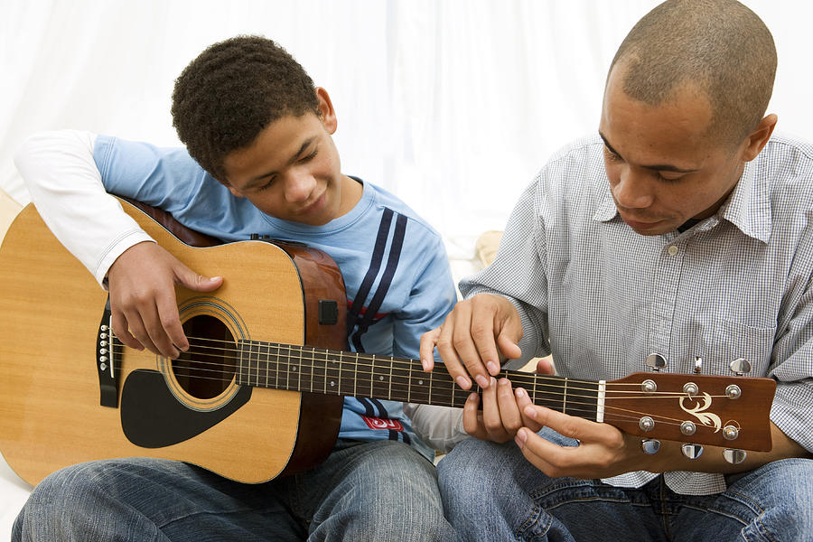 Boy learning guitar with his dad Photograph by Alistair Berg