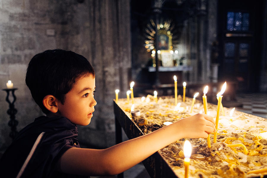 Boy lighting prayer candles Photograph by © Peter Lourenco