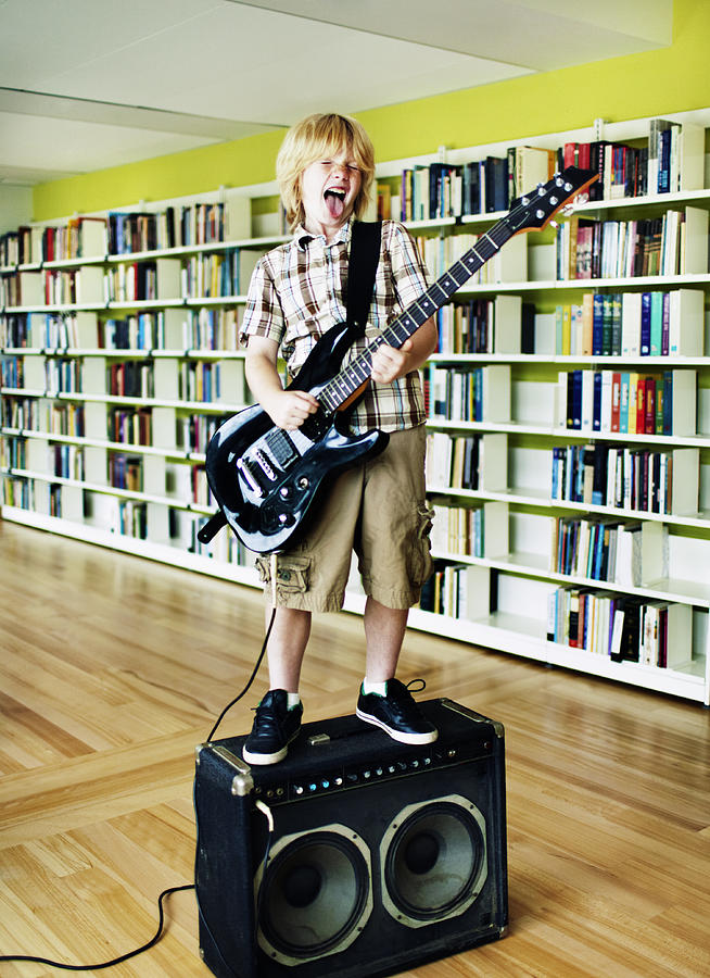 Boy Playing Electric Guitar In Library Photograph by Andy Ryan