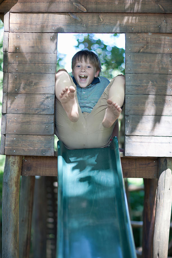 Boy playing on slide outdoors Photograph by Image Source/Zero Creatives