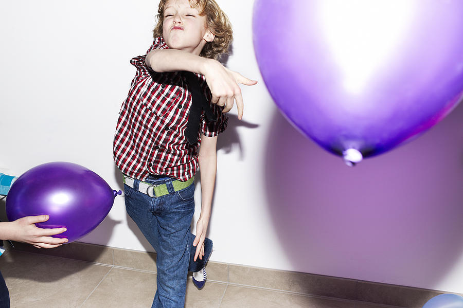 Boy playing with balloons at party Photograph by Flashpop