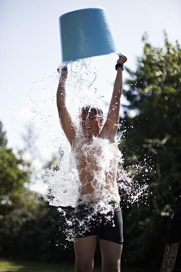 Boy pouring bucket of water on himself Photograph by Niels Busch