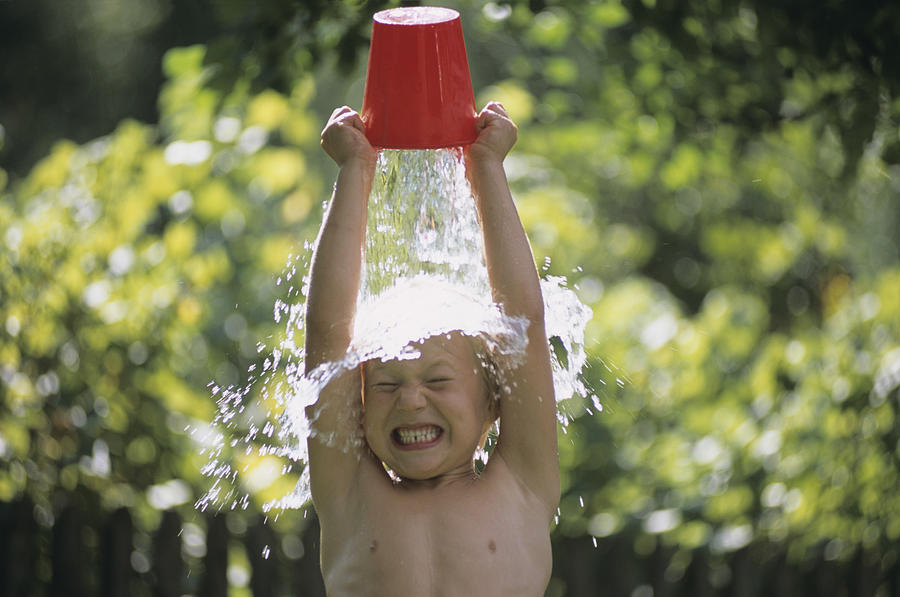 Boy pouring water over head, outdoors Photograph by Hans Huber