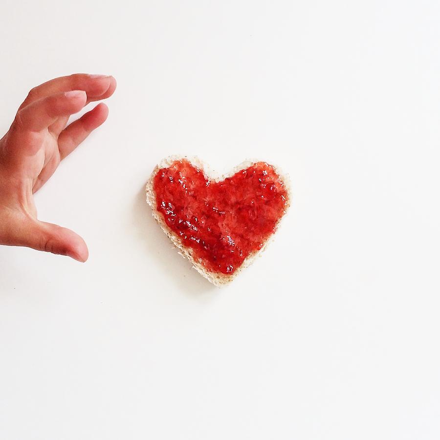 Boy reaching for heart shaped slice of bread and jam Photograph by Hannahargyle