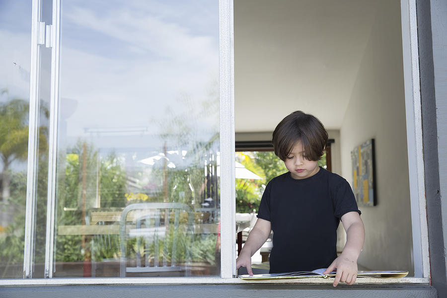 Boy reading his book at open window Photograph by David Jakle
