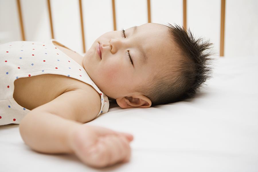Boy sleeping in crib Photograph by Image Source