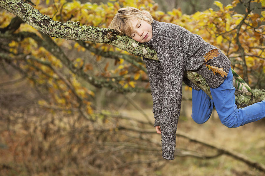 Boy sleeping on tree branch Photograph by Zing Images
