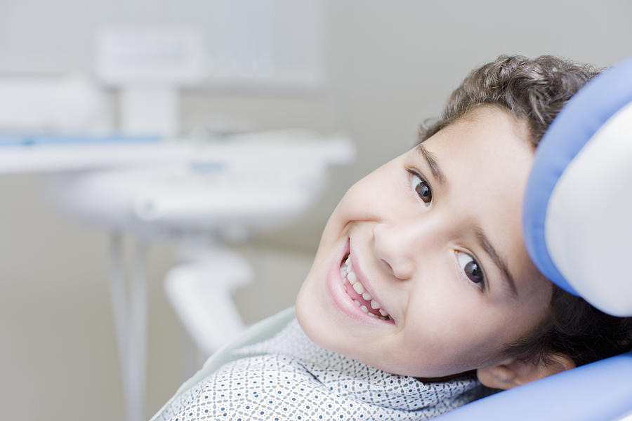 Boy smiling and sitting in dentists chair Photograph by Robert Daly
