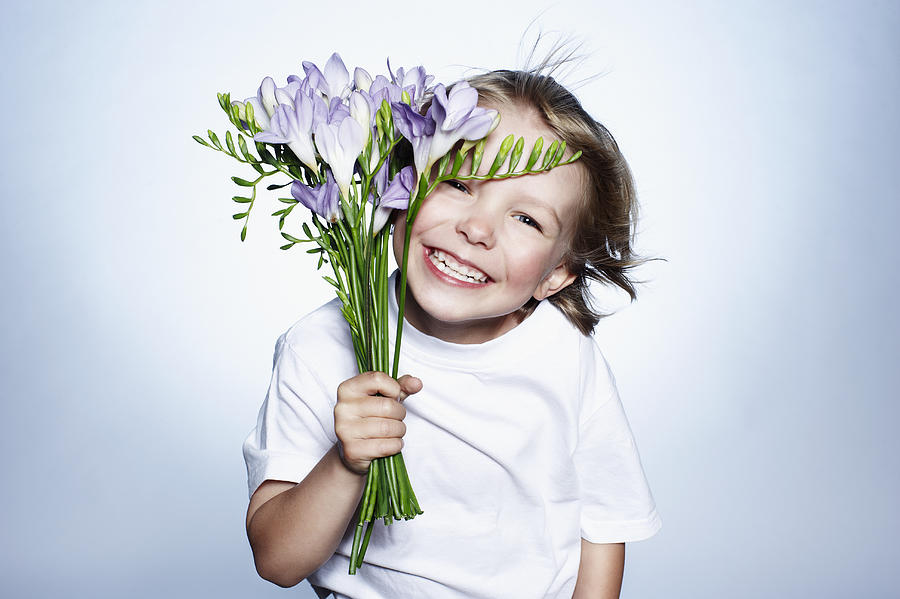 Boy smiling holding bunch of flowers Photograph by Flashpop