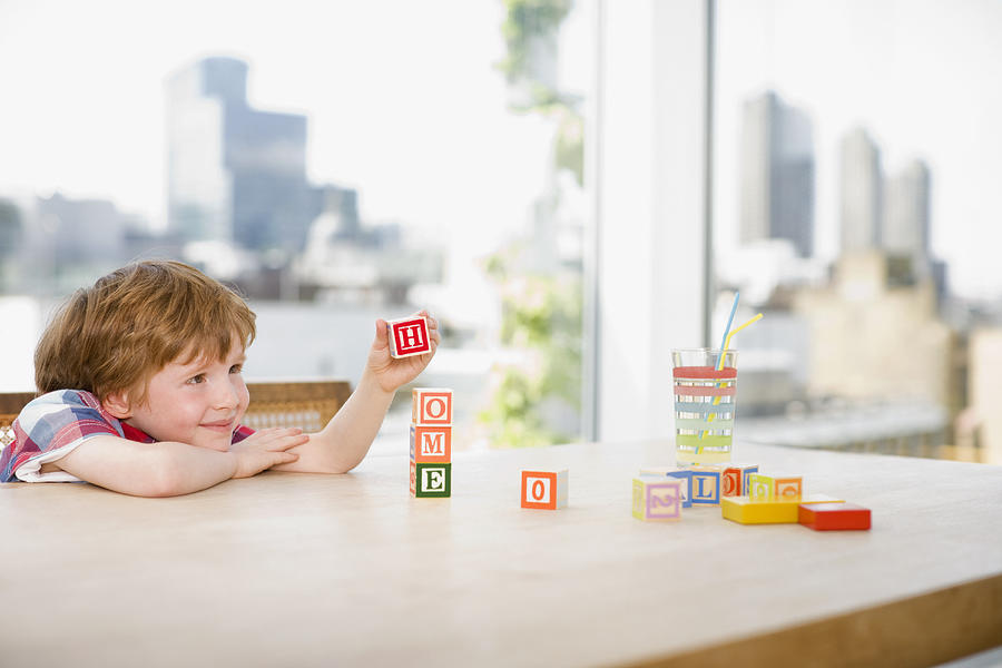 Boy stacking alphabet blocks that spell home Photograph by Robert Daly